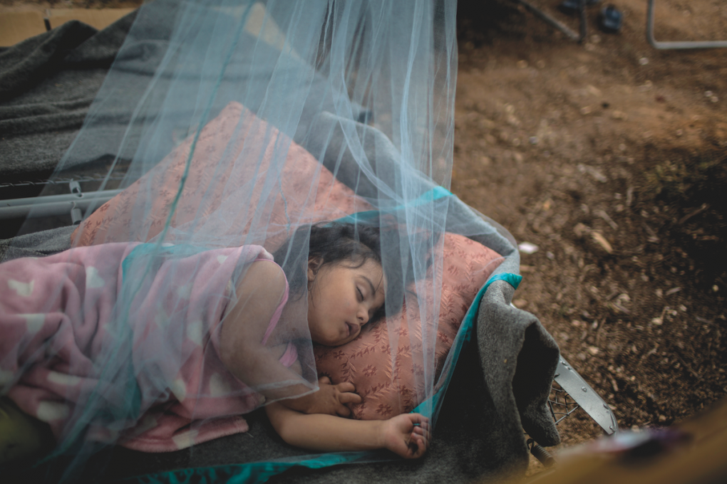 Anna Rahmoni, una rifugiata afghana di 21 mesi dorme all’aperto sotto una rete antizanzare per fuggire dal caldo asfissiante che troverebbe all’interno della tenda della sua famiglia.
